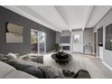 Modern living room with gray walls, beamed ceiling, fireplace, and sliding door to a balcony at 9995 E Harvard Ave # 166, Denver, CO 80231