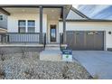 Close-up of a home's front entrance and covered porch with black pillars and a two-car garage to the side at 2750 E 102Nd Pl, Thornton, CO 80229