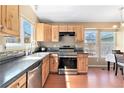 Sunlit kitchen features wood cabinets, stainless steel appliances, and black countertops at 12418 Albion St, Thornton, CO 80241