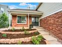Welcoming front entry with double doors, brick accents, landscaped garden beds and a cozy, covered porch at 2246 Mountain Sage Dr, Highlands Ranch, CO 80126