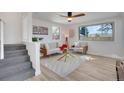 Inviting living room showcasing a large window, neutral furniture, and a cozy atmosphere with a ceiling fan and stairway at 1601 Robb St, Lakewood, CO 80215