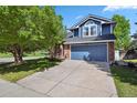 Charming two-story home with a well-manicured lawn, mature tree and a driveway leading to a blue garage door at 10291 Carrara Ter, Parker, CO 80134