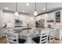 Bright, modern kitchen featuring white cabinets, a spacious island with seating, and stainless steel appliances at 15784 Burrowing Owl Ct, Morrison, CO 80465