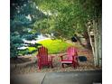 Serene outdoor seating area with Adirondack chairs, mature landscaping, and tranquil setting at 8196 Wetherill Cir, Castle Pines, CO 80108