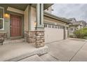 Inviting front porch with stone pillars leading to a front door and a three-car garage at 8317 Liverpool Cir, Littleton, CO 80125
