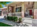 Inviting front porch with decorative columns, cozy seating, and a vibrant red front door at 4385 Oakes Mill Ct, Castle Rock, CO 80109