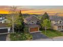 Beautiful two-story home with lush lawn, mature trees and a two-car garage under a colorful sunset at 24005 High Meadow Dr, Golden, CO 80401