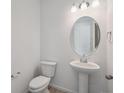 Stylish half-bathroom with a pedestal sink, an oval mirror, and modern fixtures at 24777 E 40Th Ave, Aurora, CO 80019