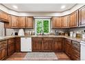 Galley kitchen with oak cabinets, sleek appliances, and a large window overlooking the green backyard at 1808 Riverview Dr, Berthoud, CO 80513