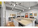 Well-equipped kitchen with breakfast bar overlooking living area and an industrial-style ceiling with track lighting at 1435 Wazee St # 504, Denver, CO 80202