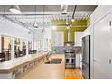 Open kitchen with stainless steel appliances, a breakfast bar with seating, and an industrial-style ceiling at 1435 Wazee St # 504, Denver, CO 80202