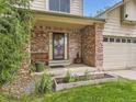 Inviting front porch with brick accents, potted plants, and bench seating near the front door at 3210 S Espana Cir, Aurora, CO 80013