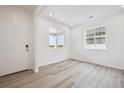 Bright, open-concept living room features light wood floors and large windows that fill the space with natural light at 45921 Wood Thrush Ave, Bennett, CO 80102