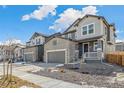 Houses with stone and siding exterior, gray garage doors, and small front porches at 13372 E 110Th Way, Commerce City, CO 80022