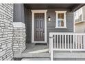 Front entrance with dark brown door, white railing, and stone accents at 13372 E 110Th Way, Commerce City, CO 80022