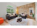 Comfortable living room with a stone accent wall, large windows, and modern furniture at 9468 E Aspen Hill Ln, Lone Tree, CO 80124