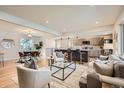 Open-concept living space with hardwood floors seamlessly flows into a modern kitchen and dining area at 6105 Lamar St, Arvada, CO 80003
