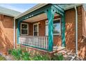 Inviting covered front porch with brick columns, charming trim, and a classic white railing and space for seating at 40 Colorado Blvd, Denver, CO 80206