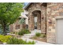 Charming home entrance with stone archway, beautiful sconces, and landscaped walkway, radiating curb appeal and warmth at 14841 W Warren Ave, Lakewood, CO 80228