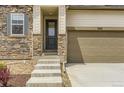 Close up of home showcasing stone facade, tan siding, attached garage, and front entryway at 3461 N Buchanan Way, Aurora, CO 80019