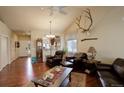 Cozy living room with hardwood floors, a ceiling fan, and rustic decor, flowing into an adjacent kitchen at 8255 E 150Th Pl, Thornton, CO 80602
