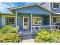 Inviting covered front porch with a cozy entrance, complemented by mature landscaping at 10116 Quivas St, Thornton, CO 80260