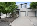 Charming two-story home with a two-car garage and a stone-accented facade is framed by mature trees in front yard at 1865 S Union Blvd, Lakewood, CO 80228