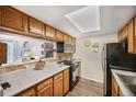 Well-lit kitchen features oak cabinets, black appliances, and an open view to stairs and living area at 1865 S Union Blvd, Lakewood, CO 80228
