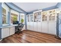 Bright home office featuring a large window, built-in storage cabinets, and stylish wood-look flooring at 9928 Sylvestor Rd, Highlands Ranch, CO 80129