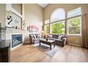 Inviting living room with high ceilings, large arched windows, a stone fireplace, and comfortable seating at 9928 Sylvestor Rd, Highlands Ranch, CO 80129