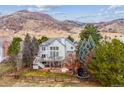 Expansive backyard with a wooden fence, lush trees, a patio area, and mountain views in the distance at 8 Mountain High Ct, Littleton, CO 80127