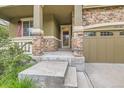 A welcoming front porch entrance with stone pillars and adjacent to a two car garage at 13424 W 64Th Pl, Arvada, CO 80004
