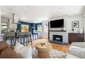 Open-concept living room with hardwood floors, white brick fireplace, and bar seating at 1650 S Holly St, Denver, CO 80222