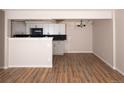 An open living room with new floors flows into the kitchen, with dark backsplash at 7255 E Quincy Ave # 205, Denver, CO 80237