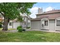 Townhome exterior with lush green lawn, mature trees, and gray siding at 10212 W 80Th Dr # C, Arvada, CO 80005