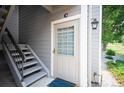 Close-up of townhome front door with grid window and adjacent staircase at 10212 W 80Th Dr # C, Arvada, CO 80005