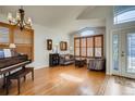 Bright living room with wood floors, plantation shutters, and grand piano by the entry at 9451 Desert Willow Trl, Highlands Ranch, CO 80129