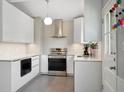 Modern kitchen with sleek white cabinets, stainless steel appliances, and stylish pendant lighting at 6705 E Jewell Ave, Denver, CO 80224