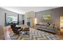 Inviting living room featuring a stylish gray sofa, sleek chairs, stone fireplace, and a chevron patterned rug at 6705 E Jewell Ave, Denver, CO 80224