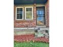 Townhome's front entrance with brick facade, security gate, and landscaping at 17437 E Rice Cir # B, Aurora, CO 80015