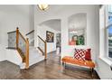 Bright entryway features hardwood floors, staircase with iron spindles, and an orange accent bench at 11845 Mobile St, Commerce City, CO 80022