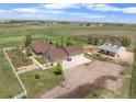 Aerial view of a ranch home with outbuildings, detached garage, and white fencing on a vast, beautiful landscape at 32501 E 137Th Way, Brighton, CO 80603