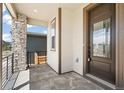 Inviting front porch featuring stone accents, a metal railing, and a dark-stained front door at 9264 Biscay St, Commerce City, CO 80022
