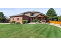 Brick home with a manicured front yard and covered porch at 5925 Zinnia Ct, Arvada, CO 80004