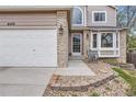Inviting front entrance with a two-car garage, brick accents, and manicured landscaping for enhanced curb appeal at 6470 S Oak Ct, Littleton, CO 80127