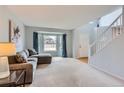 Bright living room with neutral carpet, a large bay window, and an open staircase leading to the upper level at 6470 S Oak Ct, Littleton, CO 80127