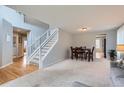 Open living space featuring hardwood floors, neutral carpet, and an open staircase, blending comfort and style at 6470 S Oak Ct, Littleton, CO 80127