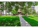 An inviting building exterior with lush green lawn, mature trees, and a welcoming entrance at 3465 S Poplar St # 506, Denver, CO 80224