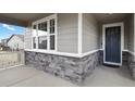 Inviting home entrance with a modern blue front door, stone veneer, and wood-look siding at 1925 Peregrine Dr, Brighton, CO 80601