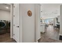 Hallway with hardwood floors leading to laundry room and the open living area at 1925 Peregrine Dr, Brighton, CO 80601